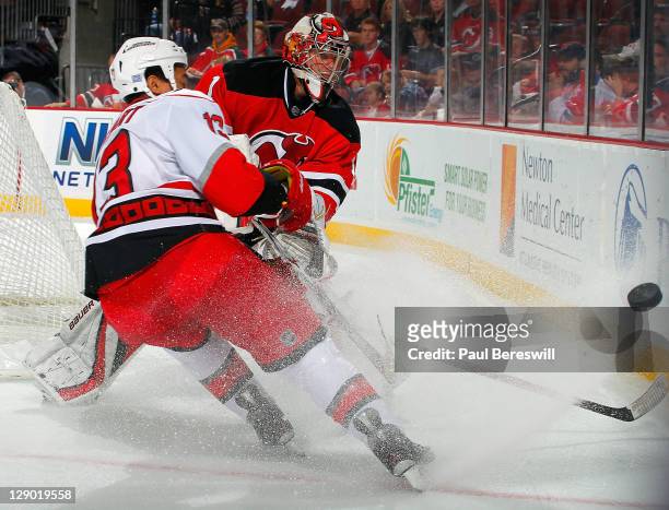 Goalie Johan Hedberg of the New Jersey Devils clears the puck from Anthony Stewart of the Carolina Hurricanes during the first period of an NHL...