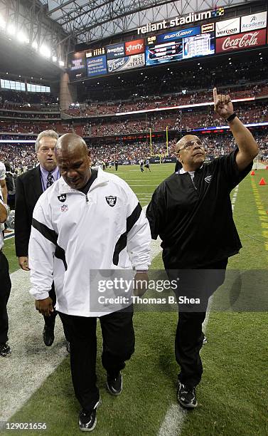 Head coach Hue Jackson and staff member Lincoln Kent of the Oakland Raiders cry and point to the heaven while leaving Reliant Stadium field after...