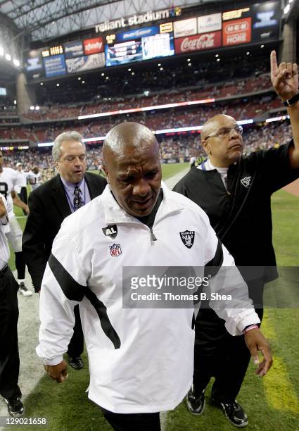 Head coach Hue Jackson and staff member Lincoln Kent of the Oakland Raiders cry and point to the heaven while leaving Reliant Stadium field after...