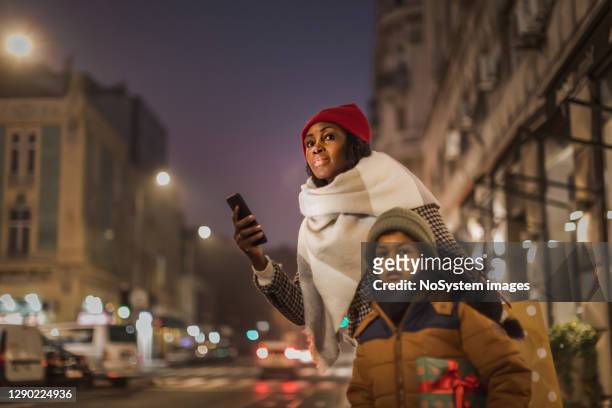 mother and son waiting for taxi after christmas shopping - taxi boys stock pictures, royalty-free photos & images