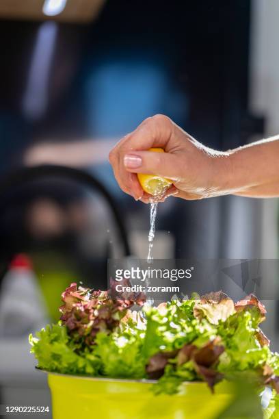 seasoning lettuce by squeezing lemon juice abundantly - leaf lettuce stock pictures, royalty-free photos & images