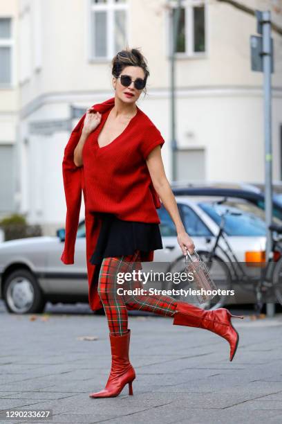 German actress Alexandra Kamp wearing a red coat by Celvin Klein, red, olive green and black checkered tights by Falke, an oversize red knitted...