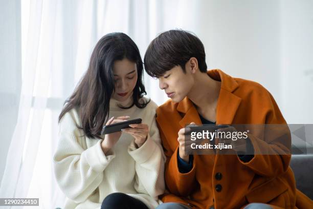 pareja joven usando el teléfono inteligente juntos - lovers 2020 film fotografías e imágenes de stock