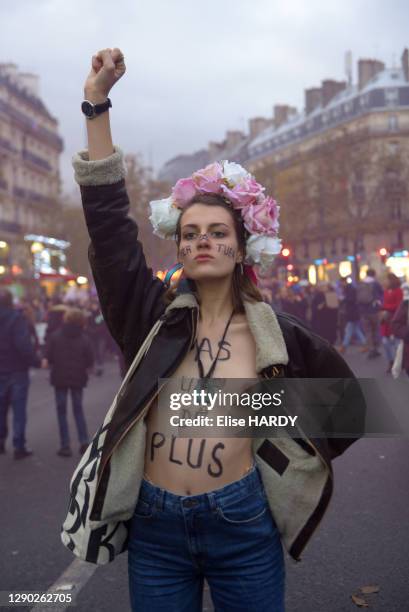 Femme brandissant le poing aux seins nus avec le slogan sur la poitrine "Pas une de plus" en soutien aux FEMEN lors de la manifestation contre les...