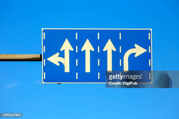 road sign against blue sky - turning fotografías e imágenes de stock