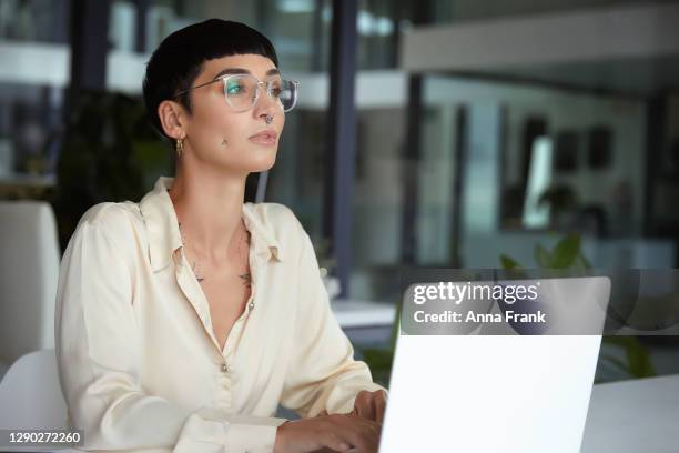 beautiful businesswoman working on her laptop at the office - alternative lifestyle stock pictures, royalty-free photos & images