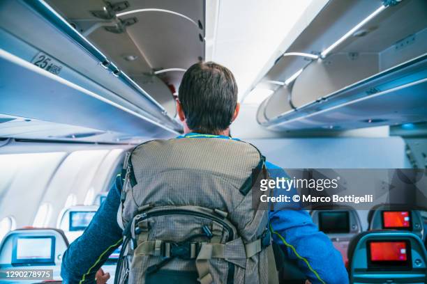 passenger with heavy backpack walking in a airplane - airplane seat back stock pictures, royalty-free photos & images