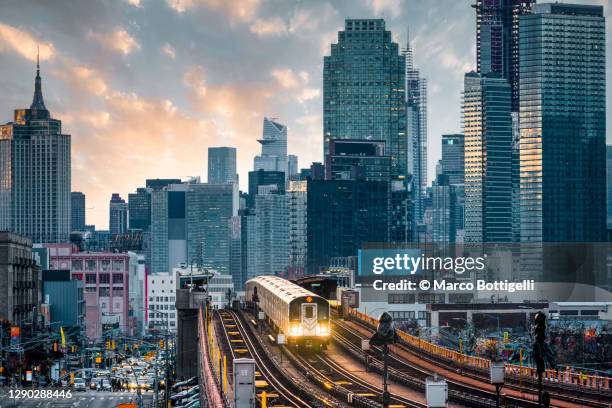 7 line subway train in queens with manhattan skyline, new york city - queens stad new york stock-fotos und bilder