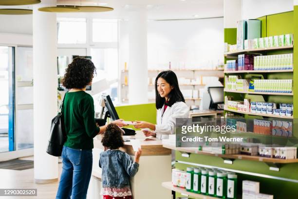 small family being served by chemist at local pharmacy - denim store stock pictures, royalty-free photos & images