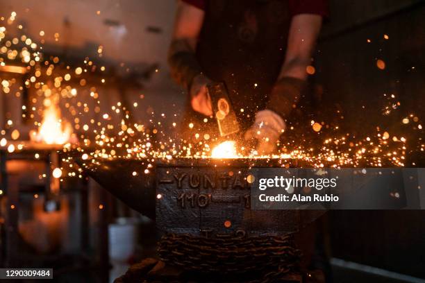blacksmith in his workshop forging his new creation. - smid stockfoto's en -beelden