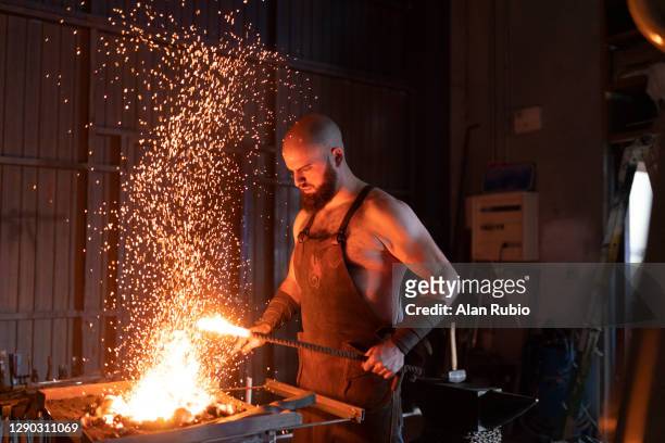 blacksmith in his workshop forging his new creation. - blacksmith sparks stock-fotos und bilder