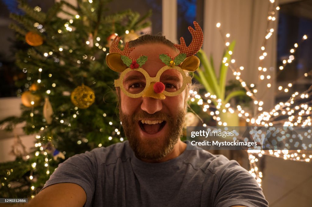 Man takes fun selfie with Christmas tree at home