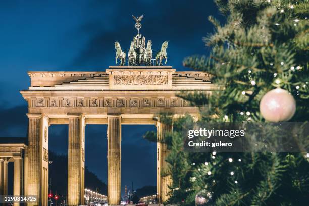 brandenburger tor behind festive iluminated christmas tree at blue hour - berlin stock pictures, royalty-free photos & images