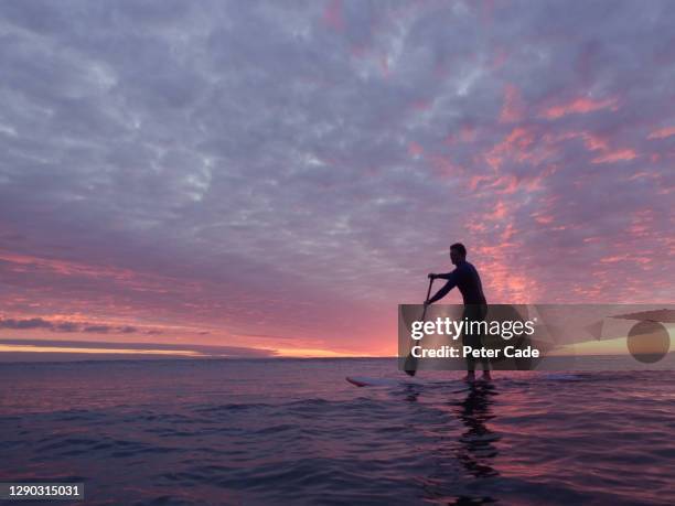 man paddleboarding at sunset - floating on water stock pictures, royalty-free photos & images