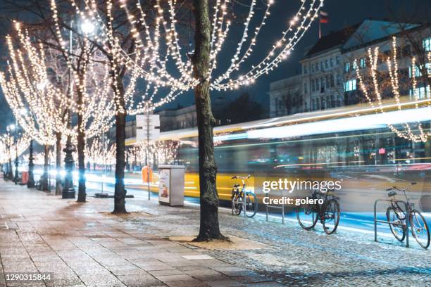 yellow bus passing festive illuminated trees unter den linden at blue hour in berlin - berlin christmas stock pictures, royalty-free photos & images