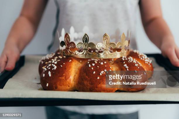 child hands holding a freshly baked homemade three king bread on baking tray. - epiphany religious celebration stock pictures, royalty-free photos & images