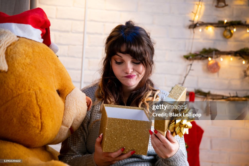 Girl is unhappy about her Christmas present, she is making a grimacing face expression.