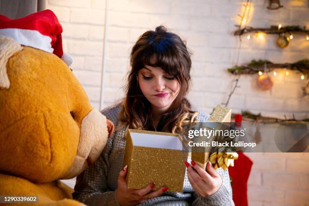 a garota está infeliz com seu presente de natal, ela está fazendo uma expressão de rosto sinistro. - open grave - fotografias e filmes do acervo