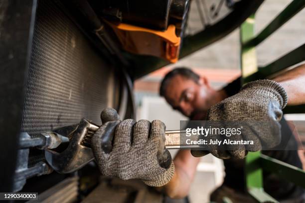 a blurred mechanic in his warehouse workshop repairs and checks his tractor - tractor repair stock pictures, royalty-free photos & images