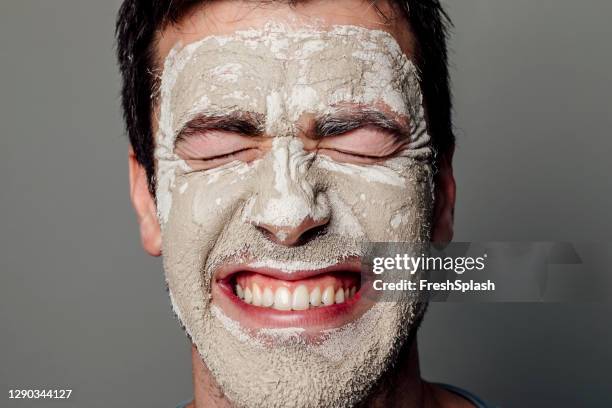 plan rapproché d’un homme caucasien souriant avec ses yeux fermés, avec un masque hydratant blanc sur son visage - blackheads photos et images de collection