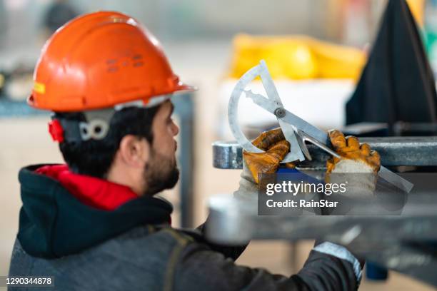 young engineer taking measurements at the factory - protractor stock pictures, royalty-free photos & images