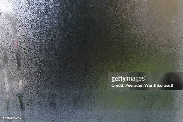 macro view of droplet of water, dew or stream on glass of window, and background of dim, foggy, hazy environment with blurry outer tree. - fog stock pictures, royalty-free photos & images