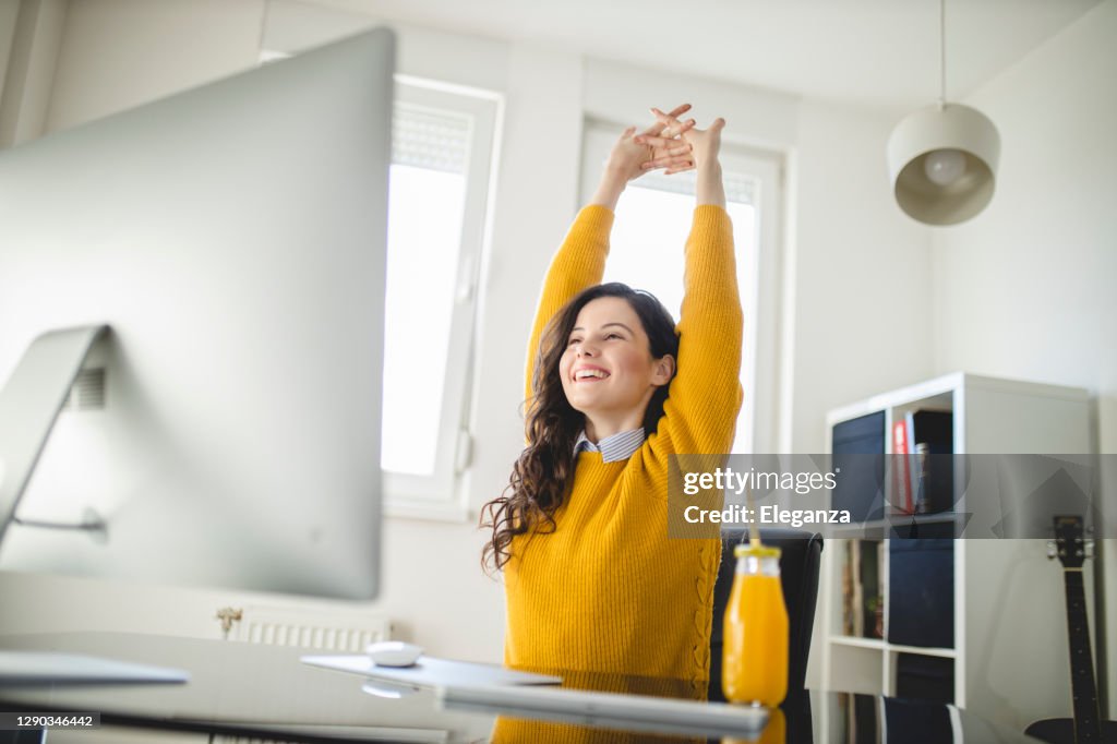 Frau dehnt sich und arbeitet zu Hause