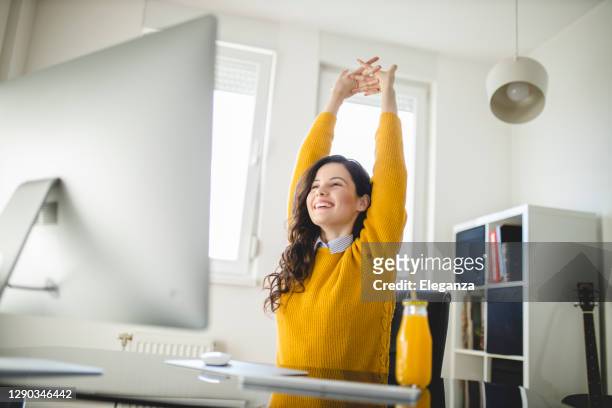 donna che si allunga e lavora a casa - scrivania foto e immagini stock
