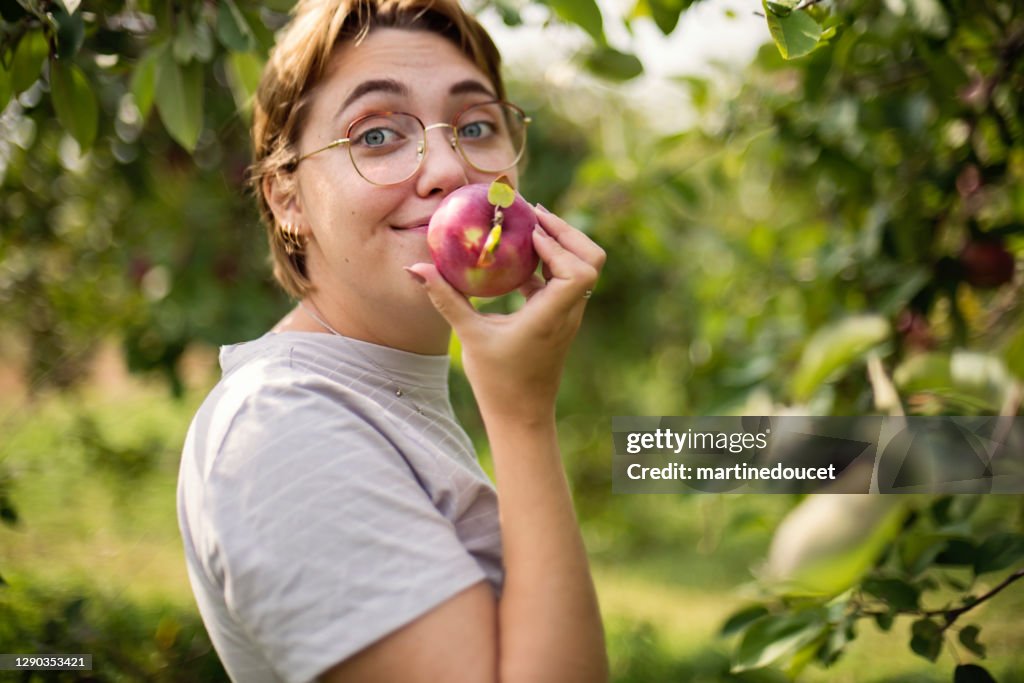 Joven adulta recogiendo manzanas en el huerto.