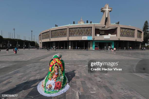 Woman wearing a dress with the image of the Virgin of Guadalupe kneels in front of the Basilica ahead of the Day Of Our Lady Of Guadalupe...