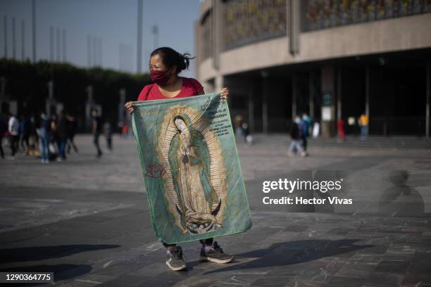 Pilgrim holds a blanket with the image of the Virgin of Guadalupe before entering a mass ahead of the Day Of Our Lady Of Guadalupe celebrations at...