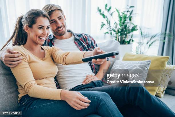 cute young couple cuddling while watching tv. - remote control stock pictures, royalty-free photos & images