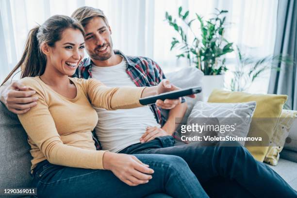 cute young couple cuddling while watching tv. - young couple at movie together imagens e fotografias de stock