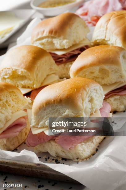 preparación de jamón al horno y deslizadores suizos en panecillos de bandeja blanca - pan de hamburguesa fotografías e imágenes de stock