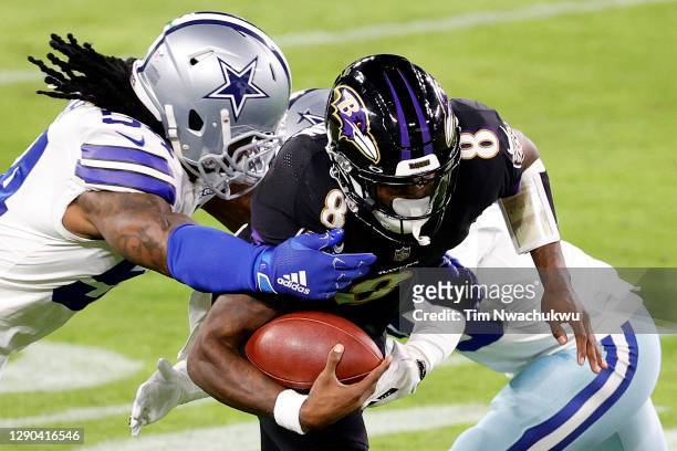 Xavier Woods and Jaylon Smith of the Dallas Cowboys tackle Lamar Jackson of the Baltimore Ravens at M&T Bank Stadium on December 08, 2020 in...