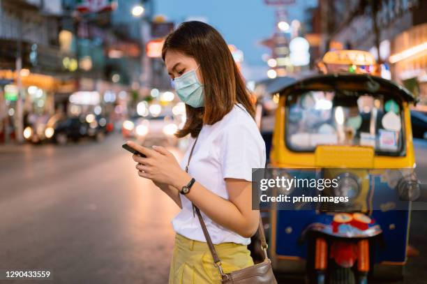 young asian solo travel use moblie phone call taxi / bus transportation at chinatown road bangkok thailand - thai tradition stock pictures, royalty-free photos & images