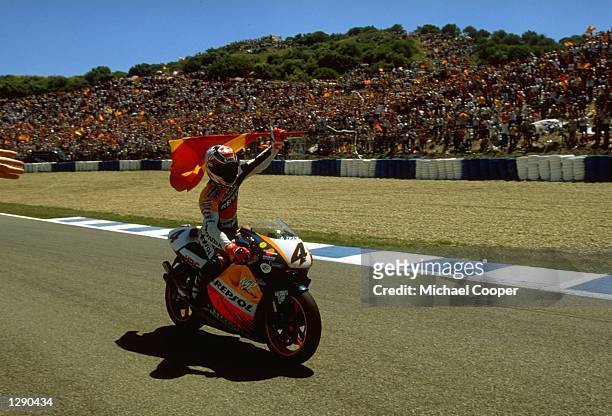 Alex Criville of Spain and Repsol Honda rides round the track with the spanish flag in his hand after the 500cc race during the 1998 Spanish...