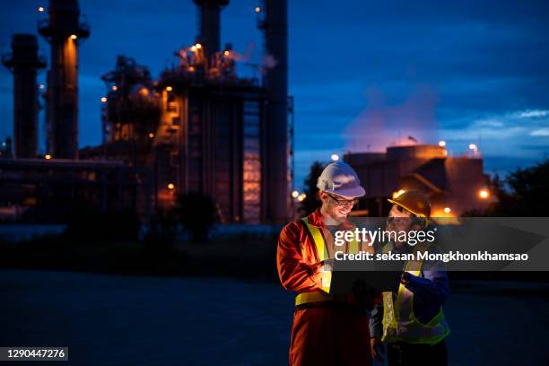 man engineer using digital tablet working late night shift at petroleum oil refinery in industrial estate. - petrochemische fabrik stock-fotos und bilder