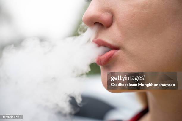 closeup of woman smoking electronic cigarette - humo de cigarrillo electrónico fotografías e imágenes de stock