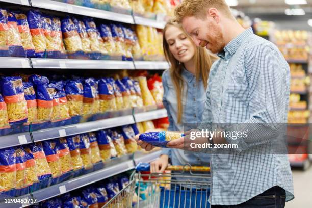 junges paar beim einkauf für pasta im supermarkt - couple in supermarket stock-fotos und bilder