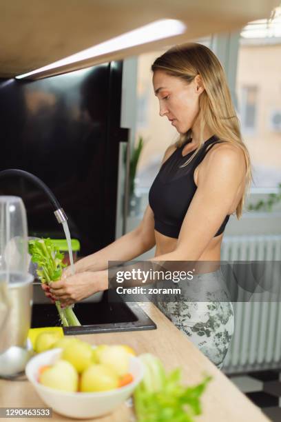 slim woman washing celery under running water in the kitchen sink - celery sticks stock pictures, royalty-free photos & images