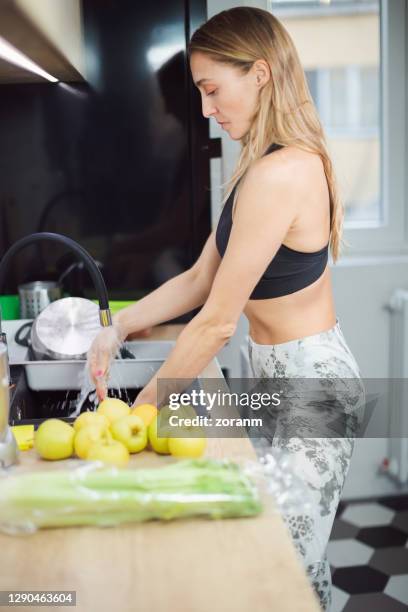 woman washing hands under tap water in the kitchen sink, apples on the counter - apple water splashing stock pictures, royalty-free photos & images