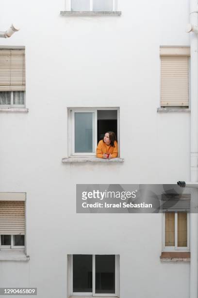 caucasian woman in yellow sweater is at the window having a cup of coffee - front view bildbanksfoton och bilder