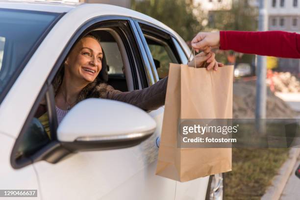 快樂成熟的女人收到她的路邊皮卡訂單 - curbside pickup 個照片及圖片檔