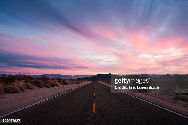 mojave desert sunset on lonely, wide open road - mojavewoestijn stockfoto's en -beelden