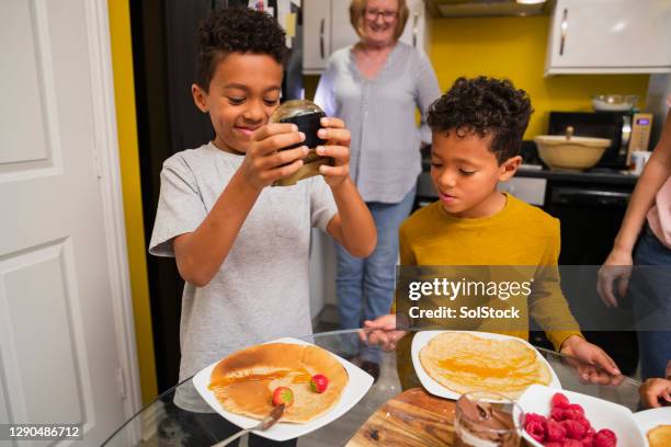 squeezing syrup on his delicious pancakes - making pancakes stock pictures, royalty-free photos & images