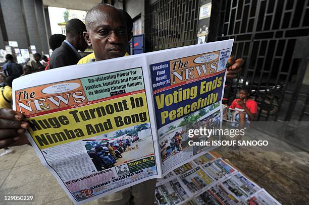 Man reads a local newspaper on a street in Monrovia on October 12 a day after Liberia's second post-war polls in which incumbent president Ellen...