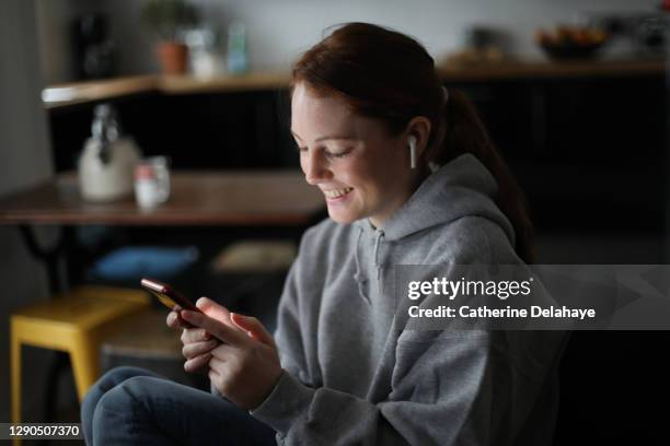 a young woman looking a her phone at home - smartphone woman photos et images de collection