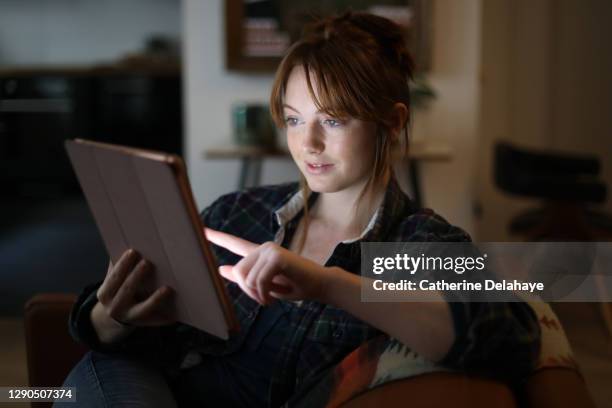 a young woman looking at a digital tablet at home - tablet screen home stock-fotos und bilder