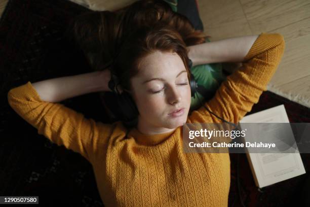 a young woman sleeping, laying on the floor, at home - headphones eyes closed stock pictures, royalty-free photos & images